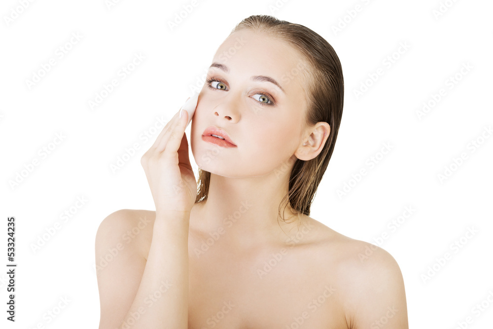 Happy young woman cleaning skin by cotton pad