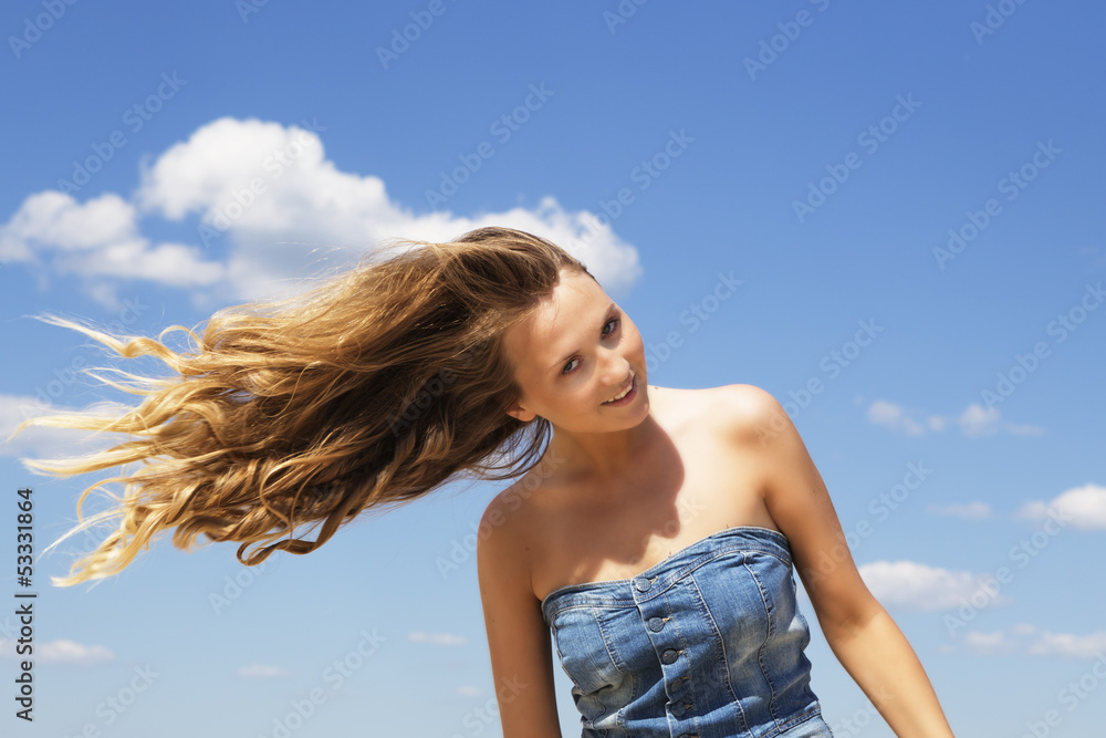 Young girl shaking her head over blue sky background Young girl shaking her head over blue sky background