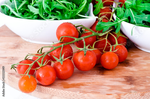 tomatoes and rucola in white cups over wooden board