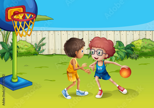 Two boys playing basketball inside the fence