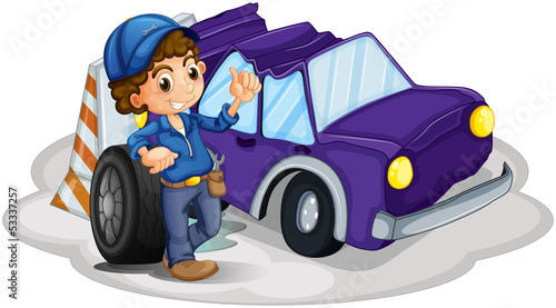 A boy standing in front of a wheel beside the damaged car