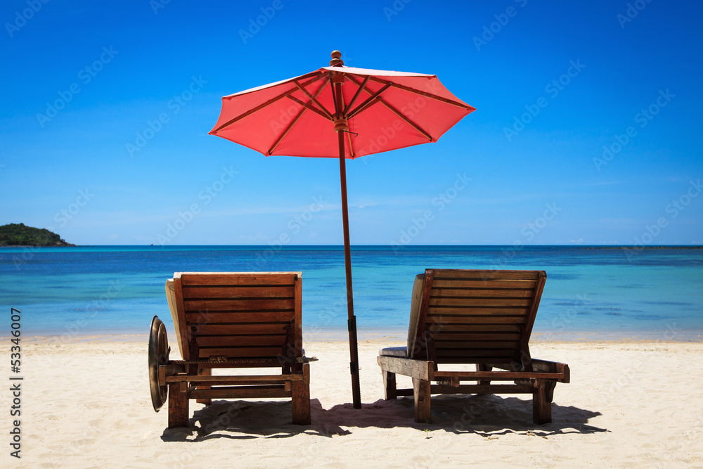 Два лежака и зонт от солнца на песчаном пляже