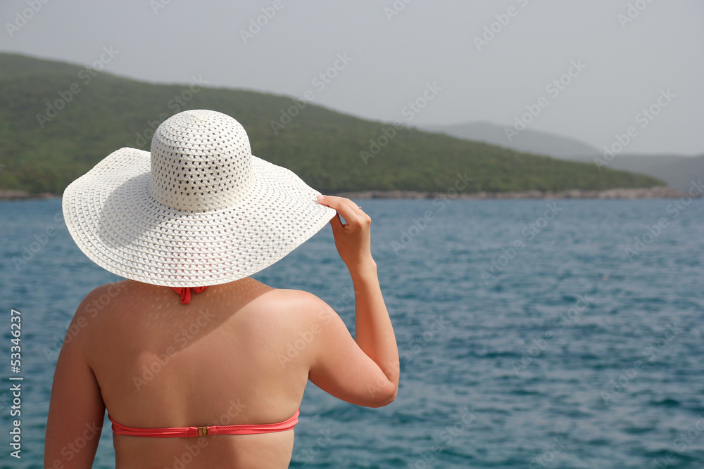 woman in swimsuit and white hat on the beach