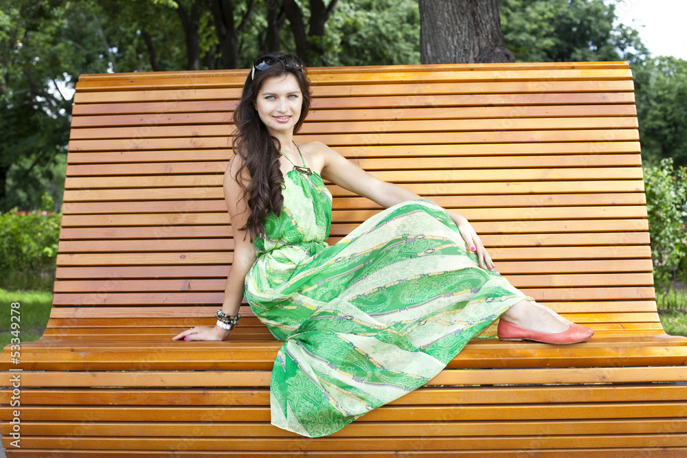 Brunette sitting on a bench in a summer park Brunette sitting on a bench in a summer park