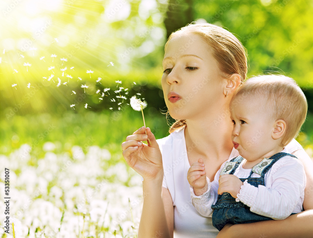happy family. Mother and baby girl blowing on a dandelion flower happy family. Mother and baby girl blowing on a dandelion flower