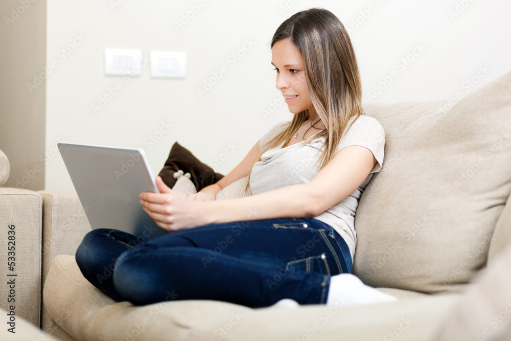 Woman using a laptop while relaxing on the sofa Woman using a laptop while relaxing on the sofa