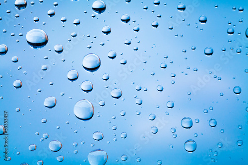 Macro photo of water drops on glass above blue blurred sky