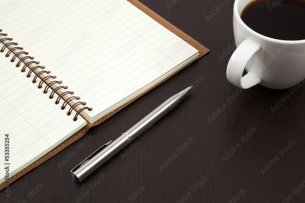 Cup of coffee on a wooden table with book and pen Cup of coffee on a wooden table with book and pen