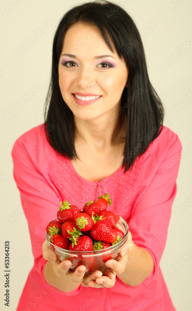 Beautiful young woman with strawberries on grey background Beautiful young woman with strawberries on grey background