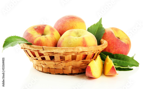 Ripe sweet peaches with leaves in basket  isolated on white