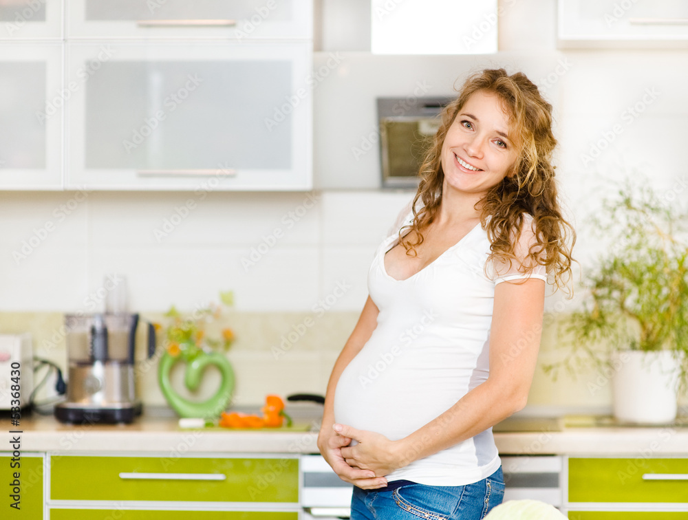 Portrait of beautiful pregnant woman holding belly in kitchen Portrait of beautiful pregnant woman holding belly in kitchen