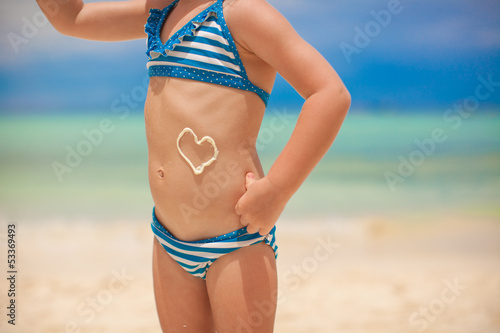 Close-up heart painted by sun cream on little girl's belly