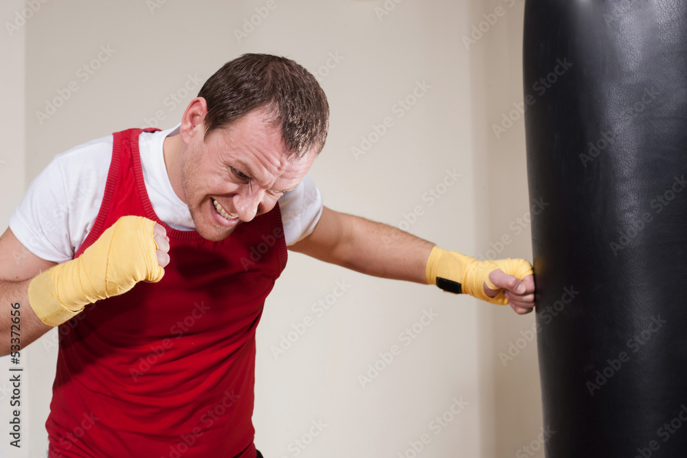 Man in boxing gloves makes a series of exercises punching bag
