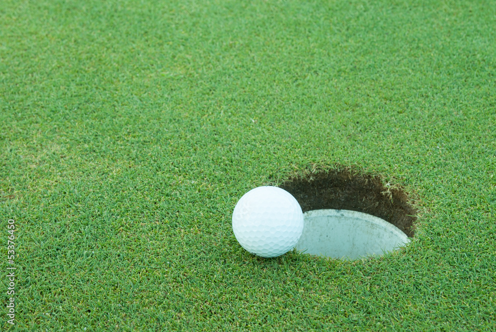 A golf ball very close to a hole A golf ball very close to a hole