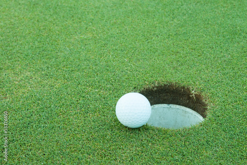 A golf ball very close to a hole
