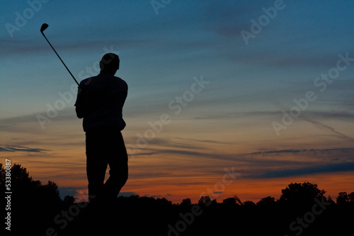 Golfer teeing off at dusk