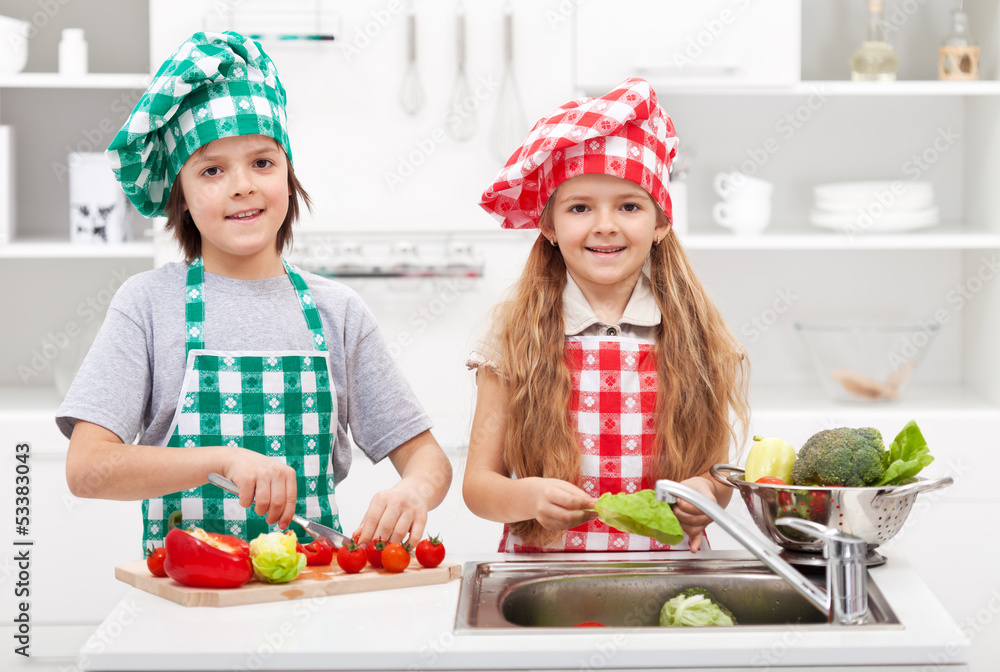 Kids helping in the kitchen - washing and slicing vegetables Kids helping in the kitchen - washing and slicing vegetables