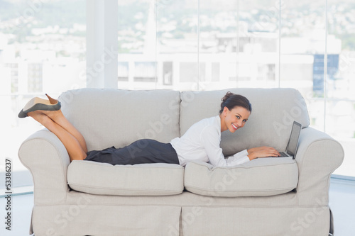 Business woman lying on couch with laptop