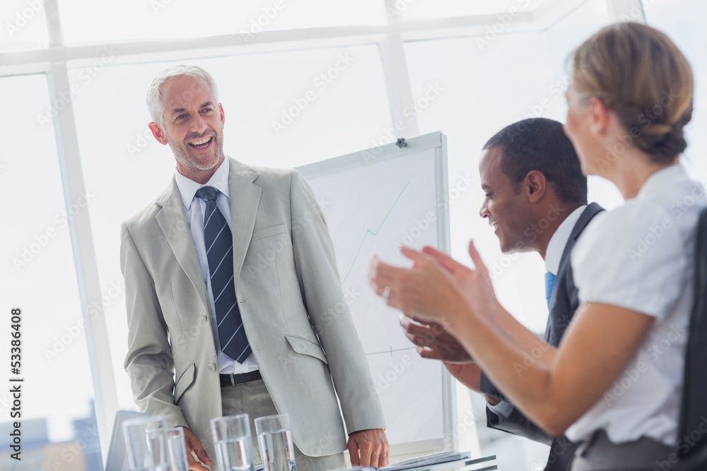 Colleagues applauding smiling manager during a meeting Colleagues applauding smiling manager during a meeting