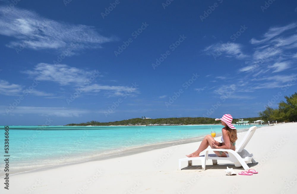 Girl with a glass of orange on the beach of Exuma, Bahamas