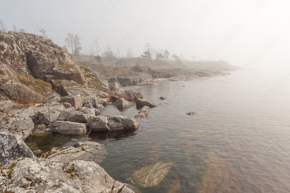 Fog on stony coast of lake.  spring landscape