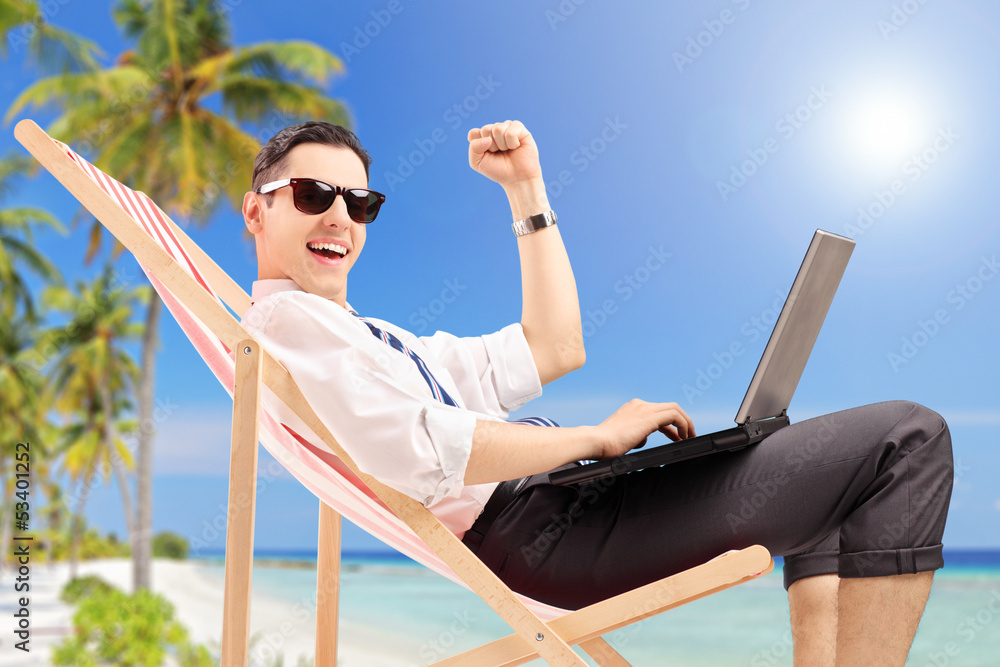 Happy businessman with a laptop on a beach