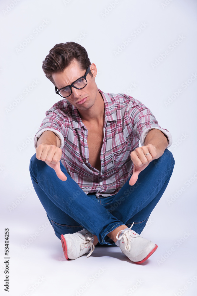 casual man sits and shows thumbs down casual man sits and shows thumbs down