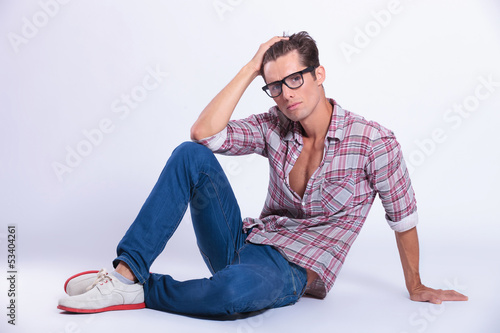 casual man sits on the floor with hand in hair © Viorel Sima