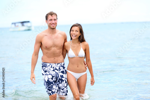 Beach couple in love walking happy in water