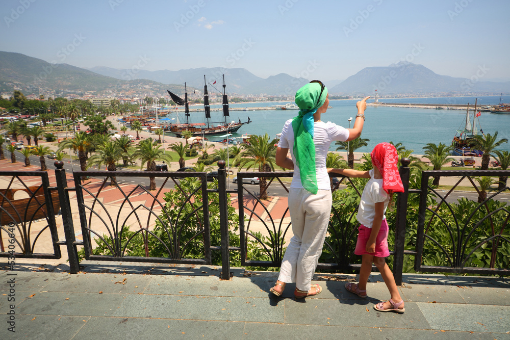 Obraz premium Mother and daughter walking along promenade and view ships
