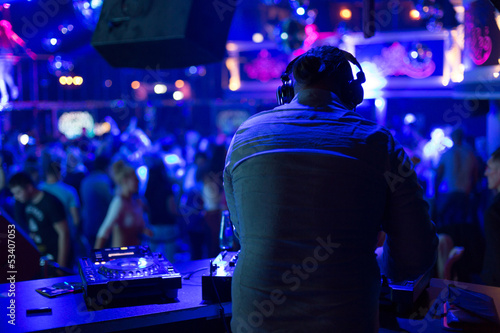 DJ turns the records at the club under the blue light