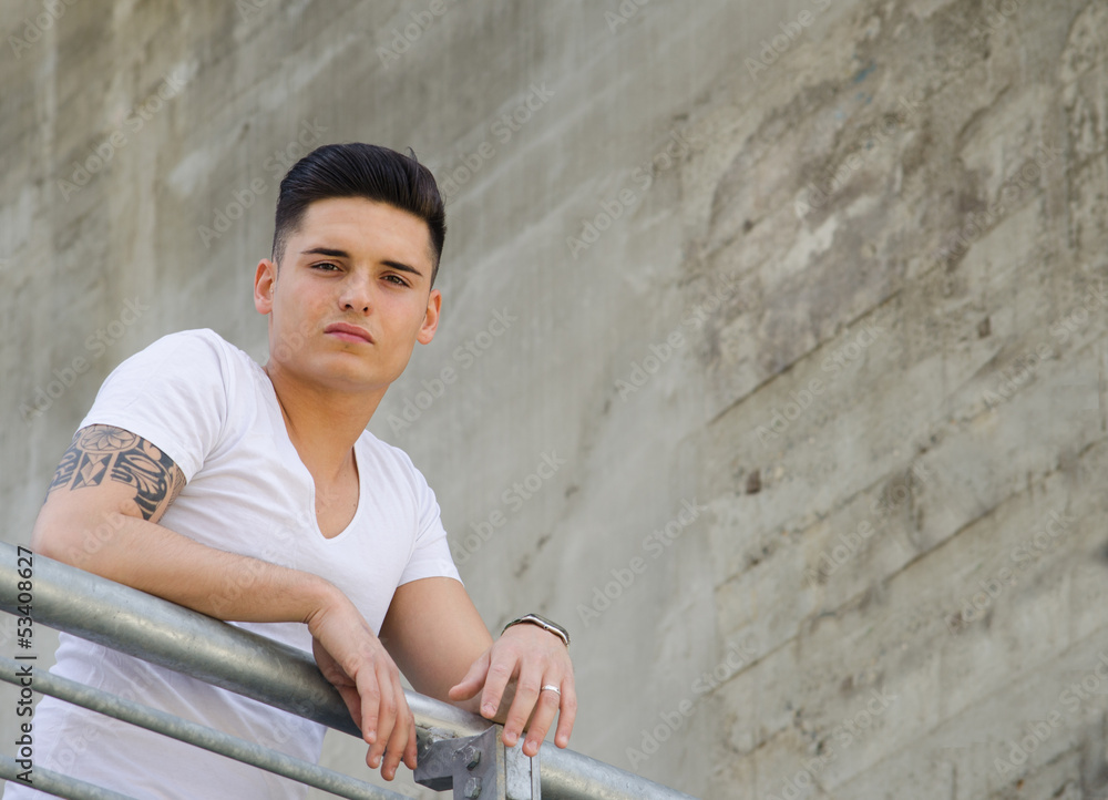 Handsome young man leaning on railing, large copyspace