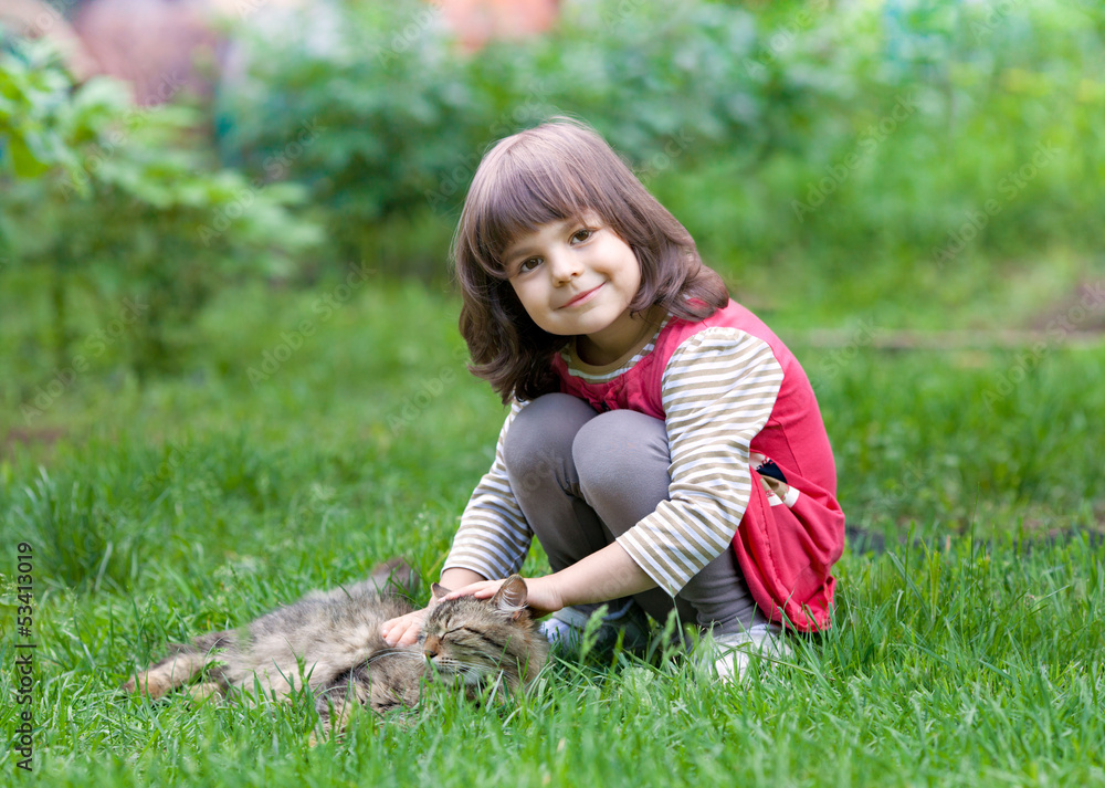 Fototapeta premium Happy little girl playing with cat on the grass