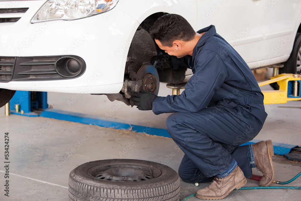 Young mechanic fixing the brakes of a car at an auto shop