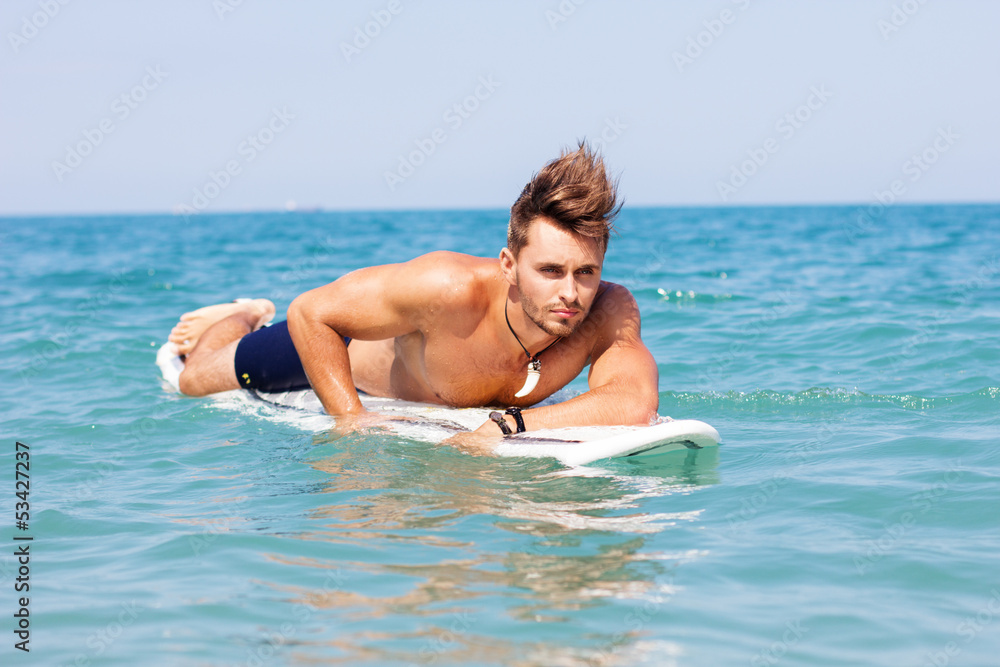 Strong young surf man portrait at the beach with a surfboard