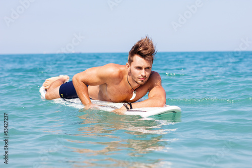 Strong young surf man portrait at the beach with a surfboard