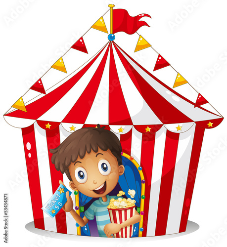 A young boy with a ticket and a popcorn near the tent