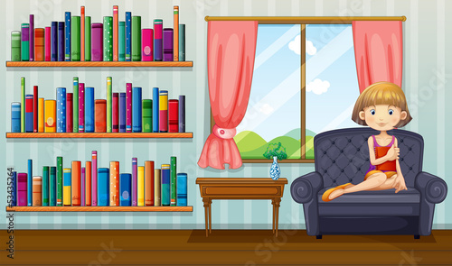 A girl sitting on a sofa holding a book inside the house