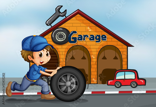 A young man pushing the tire in front of the garage