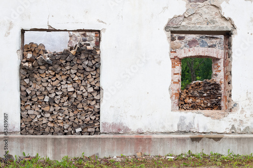 Firewood pile in window hole of old building