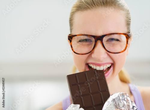 Fotografie Happy teenage girl eating chocolate bar