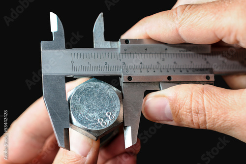 Hands calibrating an steel bolt