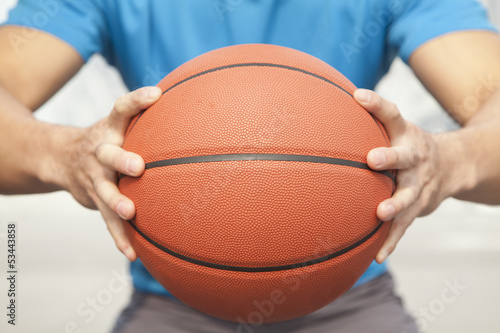 Close up of young man, midsection, holding a basketball