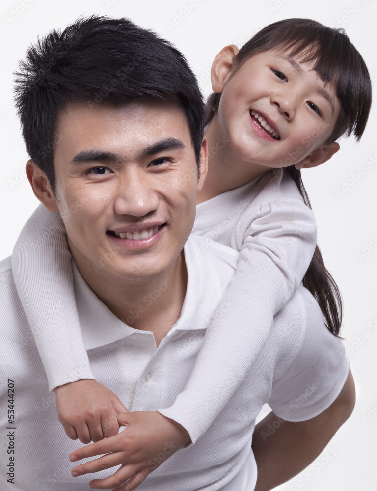 Father carrying daughter on back, studio shot Father carrying daughter on back, studio shot
