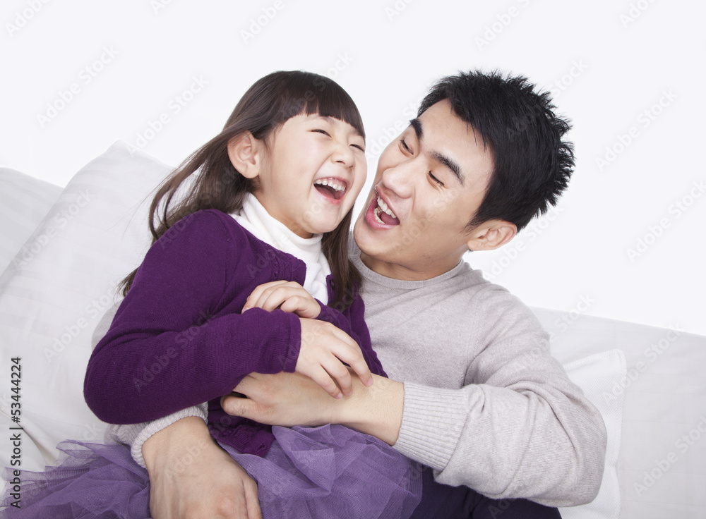 Father tickling daughter on the sofa, studio shot Father tickling daughter on the sofa, studio shot
