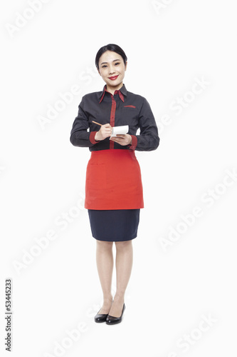 Young Waitress writing order on note pad, smiling, studio shot