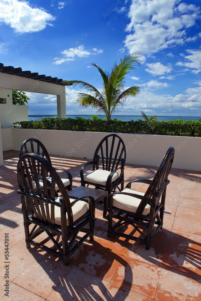 Chairs and little table on tropical terrace overlooking sea