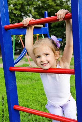 Happy little girl on outdoor playground equipment
