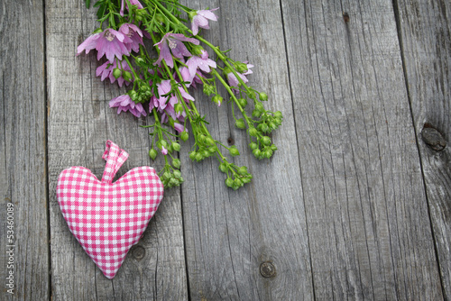 Rustic still life with a bouquet of pink flowers and heart on a photo