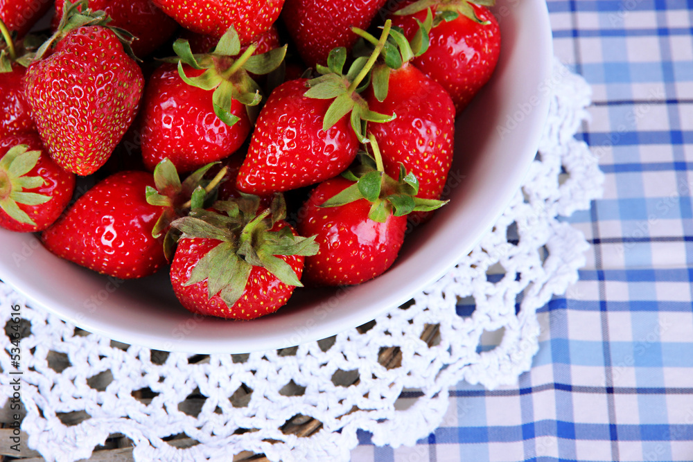 Strawberries in plate on wicker stand on napkin close-up Strawberries in plate on wicker stand on napkin close-up